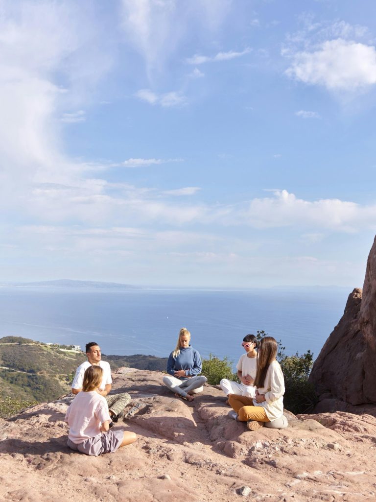 Gruppe von fünf Personen sitzt im Freien mit Blick aufs Meer.
